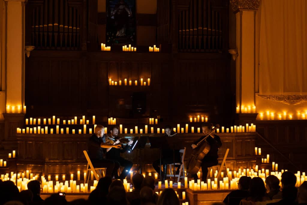 A string quartet performing on a stage lit by candles.