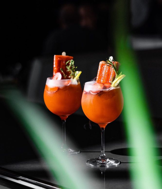 An image of two red cocktails with popsicles inside 