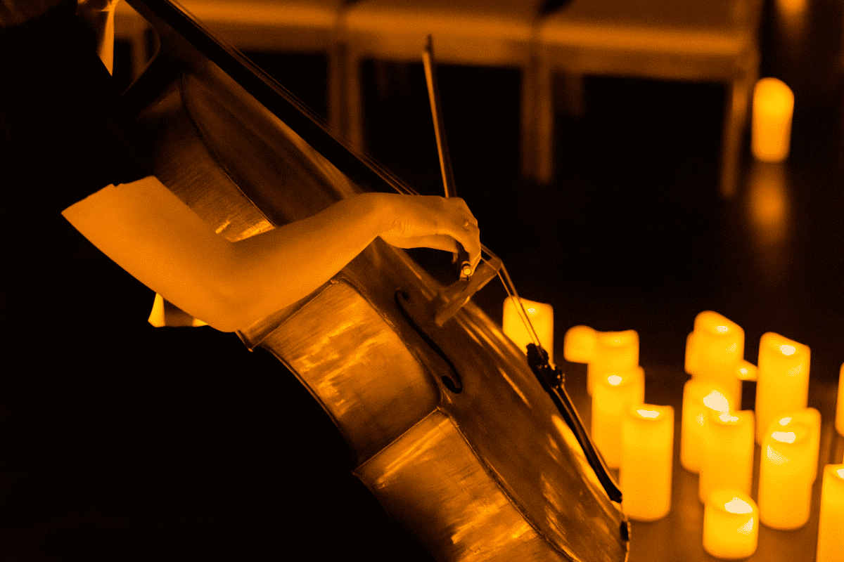 A close up of a woman playing the cello in the glow of candlelight.