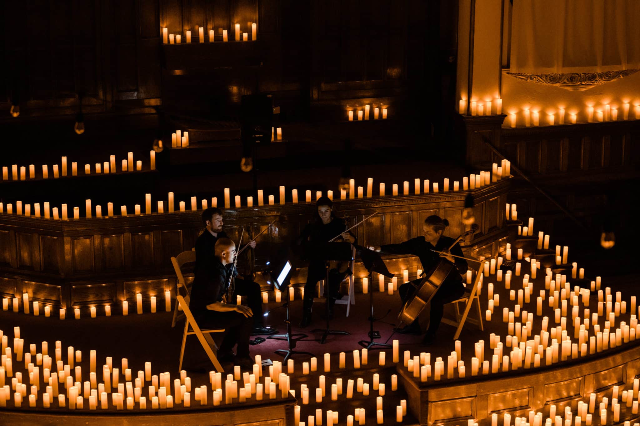 string quartet on stage surrounded by candles for a candlelight concert