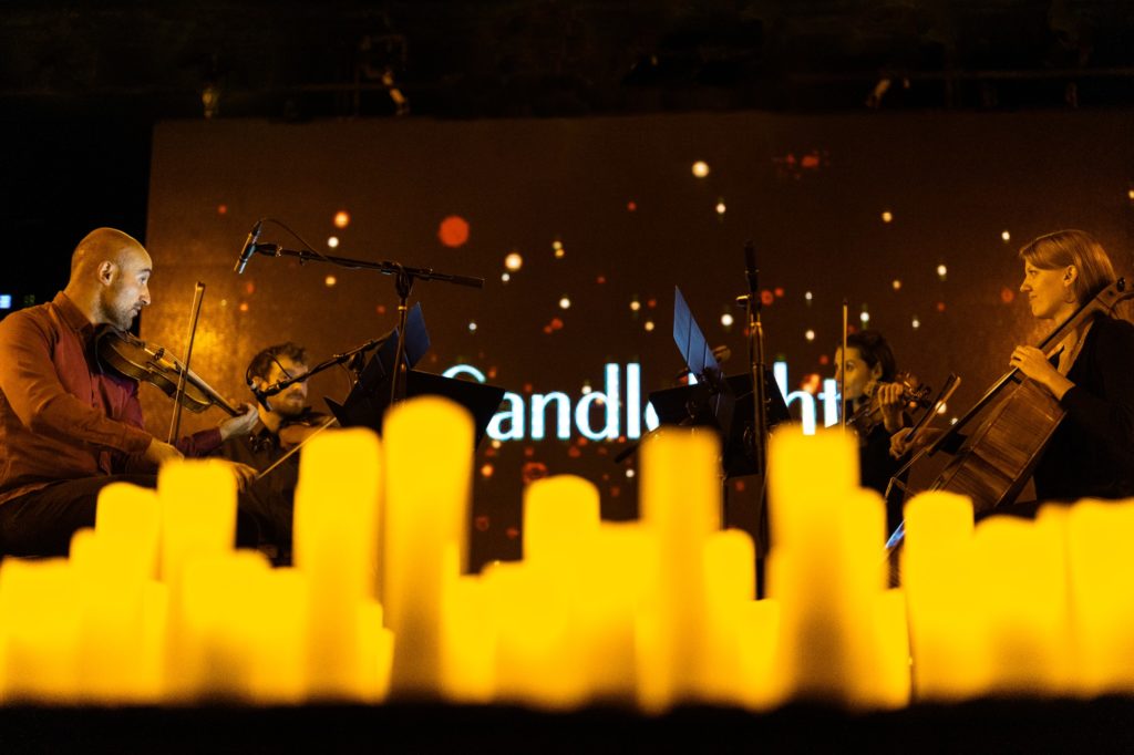 musicians performing on stage surrounded by candles