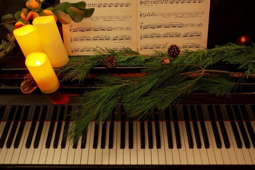 A piano decorated with Christmas foliage and candles for a Candlelight holiday special.